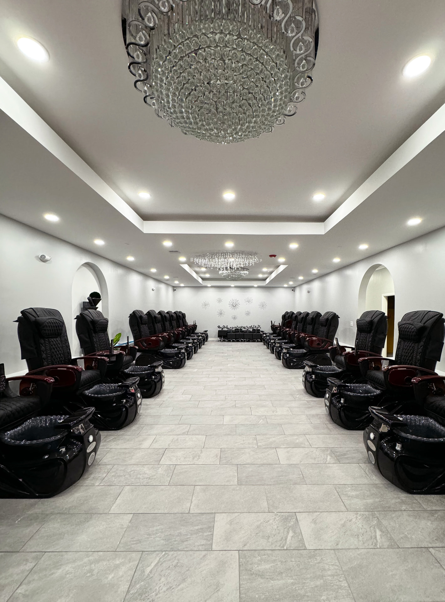 Interior of Divine Nails & Spa with rows of pedicure chairs and crystal chandeliers