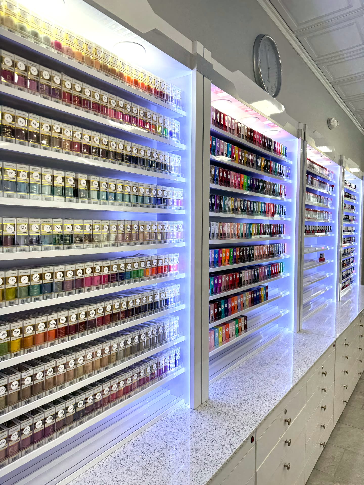 Illuminated shelves holding hundreds of nail polish colors